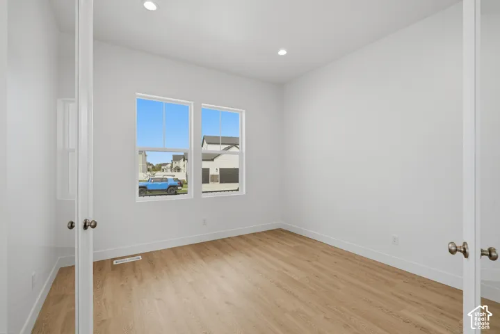 Room featuring white double-panel doors, wood-finish flooring, recessed lighting, and dual windows