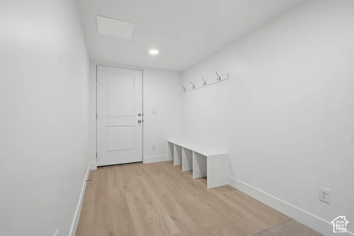 Mudroom area featuring wood-finish flooring, built-in storage cubbies, wall-mounted coat hooks, and recessed lighting