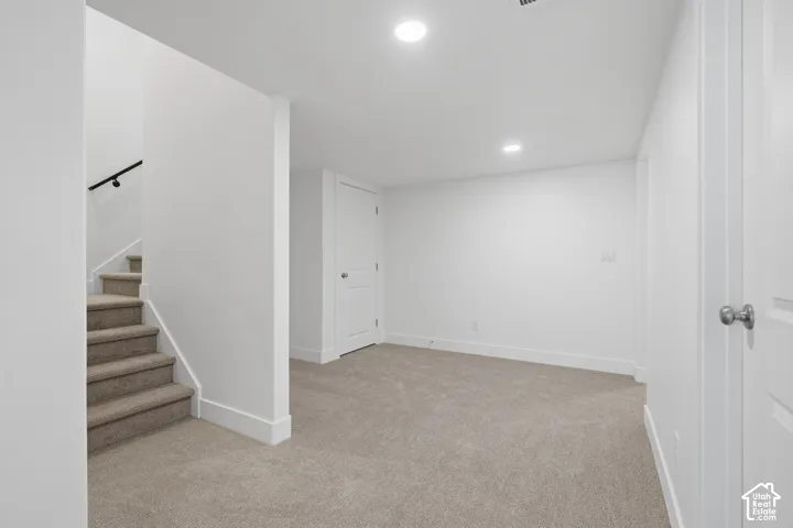 Neutral-toned carpeting, recessed ceiling lighting, and solid-core interior doors