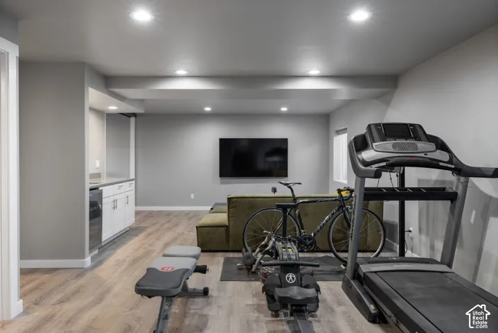 Recessed lighting, wood-finish flooring, and built-in cabinetry featuring a stone-surface countertop and under-counter beverage refrigerator