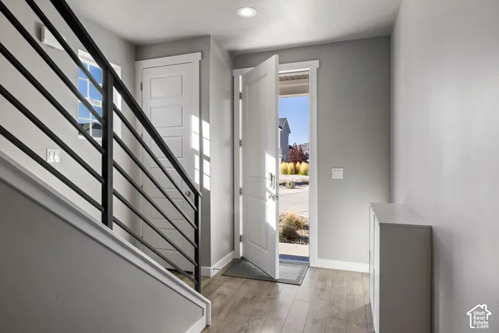 Entryway featuring wood-finish flooring, matte black horizontal railing, recessed lighting, and a multi-panel door