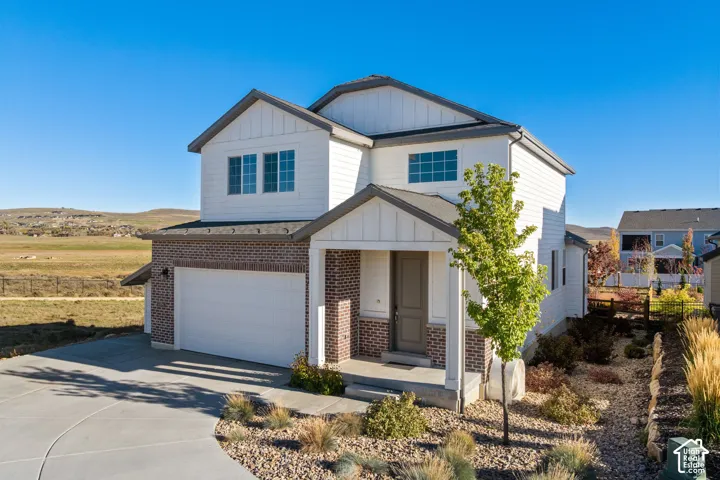 Two-story residence featuring a mixed-material exterior of horizontal siding and brick masonry, a covered front entryway, an attached two-car garage, and desert-inspired rock landscaping
