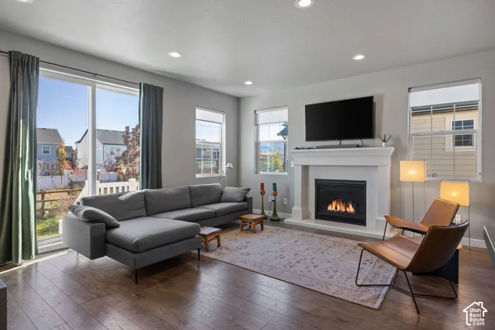 Living area featuring wood-finish flooring, a white fireplace surround with a gas insert, recessed lighting, and large windows