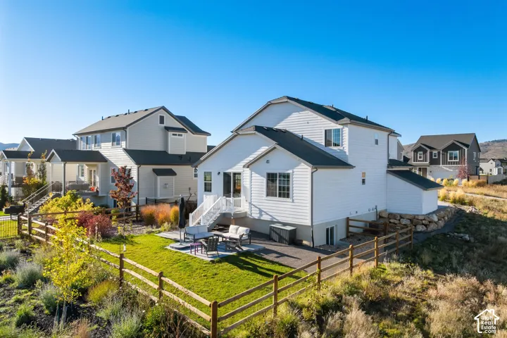 Two-story residence featuring white horizontal siding, a fenced backyard, a paver patio, and elevated rear deck stairs