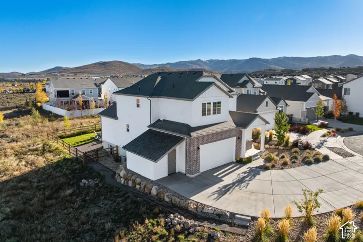 Two-story residence featuring a multi-gabled roofline, white horizontal siding, brick masonry detailing, an attached two-car garage, and a curved concrete driveway