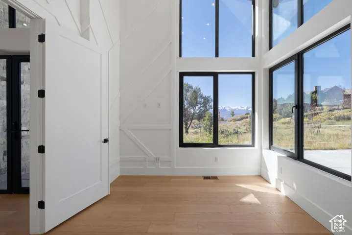 Double-height ceilings featuring floor-to-ceiling windows with black frames, wood-finish flooring, and geometric wall paneling