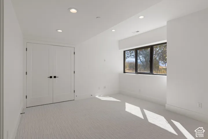 Interior space featuring neutral carpeting, double doors with matte black hardware, recessed ceiling lighting, and a window with dark-toned frames