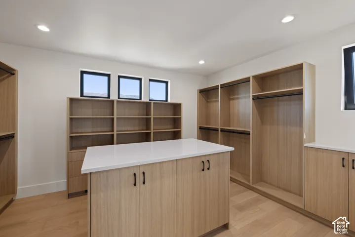 Custom wood-finish cabinetry, central island with quartz countertop, wood-finish flooring, recessed lighting, and trio of windows
