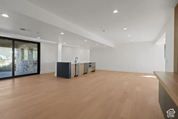 Open-concept interior featuring light wood-finish flooring, recessed lighting, and large sliding glass doors