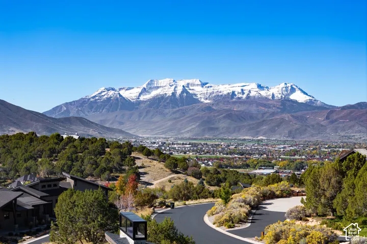 Panoramic mountain backdrop featuring snow-capped peaks, surrounding terrain with native vegetation, and winding paved roadway