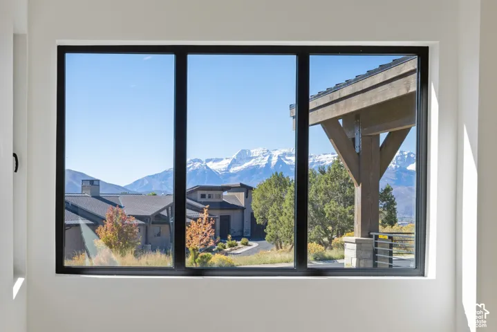 Large picture window with a dark frame showcasing a mountain backdrop and timber-framed exterior structure
