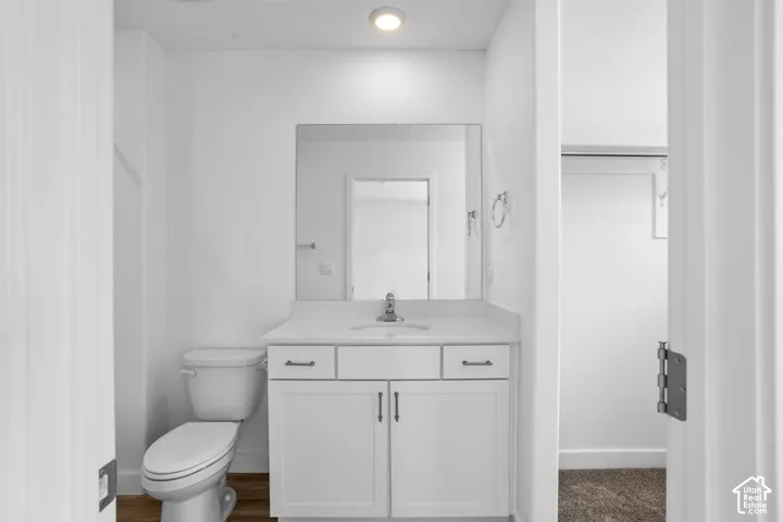 Bathroom featuring a white vanity cabinet with drawers, a solid-surface countertop with an integrated basin, a polished chrome faucet, a wall-mounted rectangular mirror, and recessed lighting