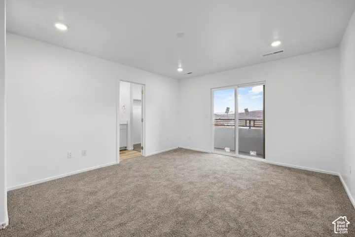 Neutral-toned carpeting, recessed ceiling lighting, sliding glass door, and exterior balcony