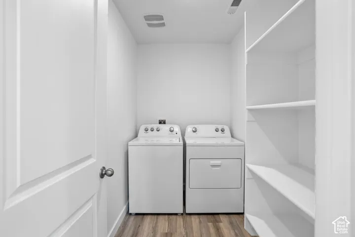 Utility space featuring wood-finish flooring, built-in white shelving, and laundry hookups