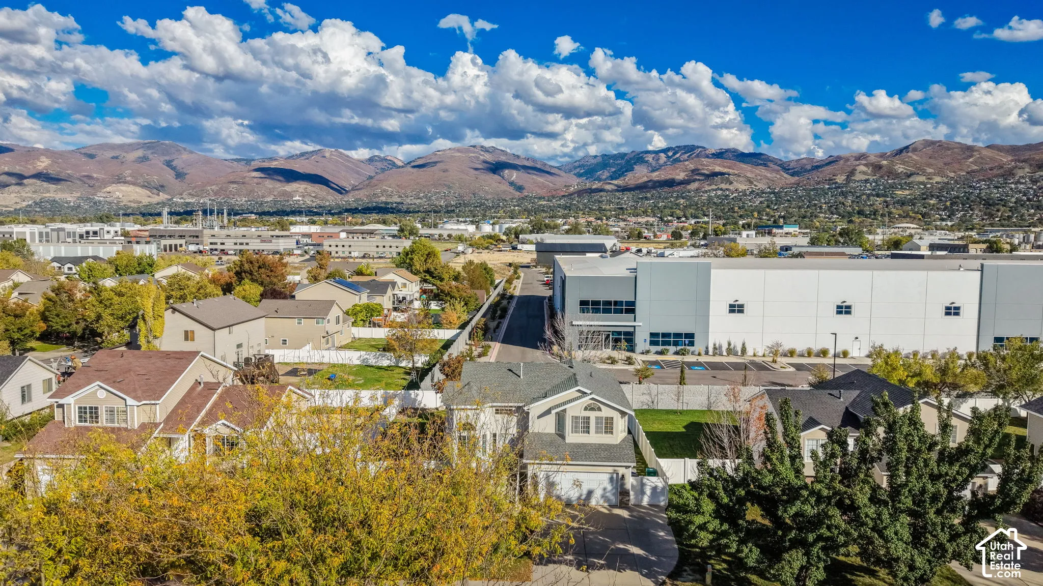 Two-story residential structure featuring a shingled roof, attached garage, and mountain backdrop