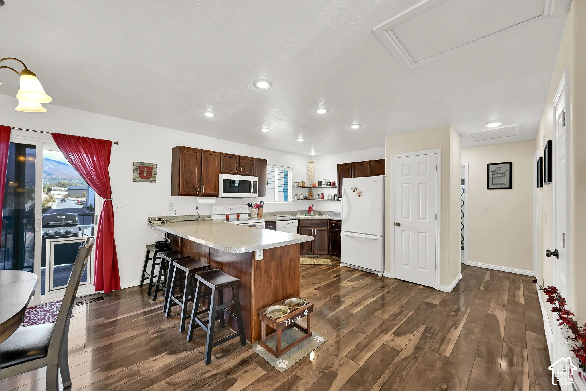 Kitchen featuring wood-finish flooring, a central island with a breakfast bar, stained wood cabinetry, recessed lighting, and a sliding glass door