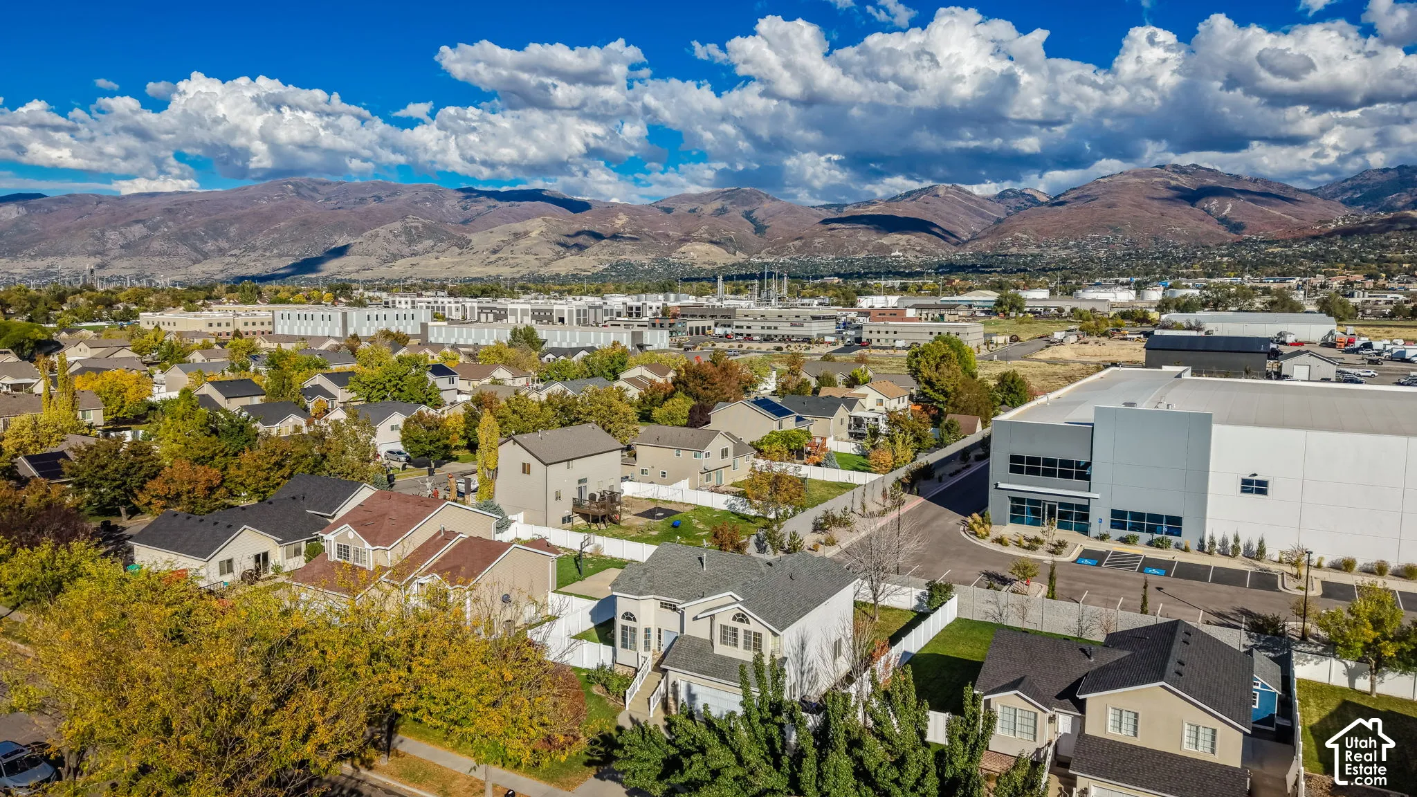 Aerial perspective showcasing residential structures with fenced backyards, situated against a backdrop of prominent mountain ranges