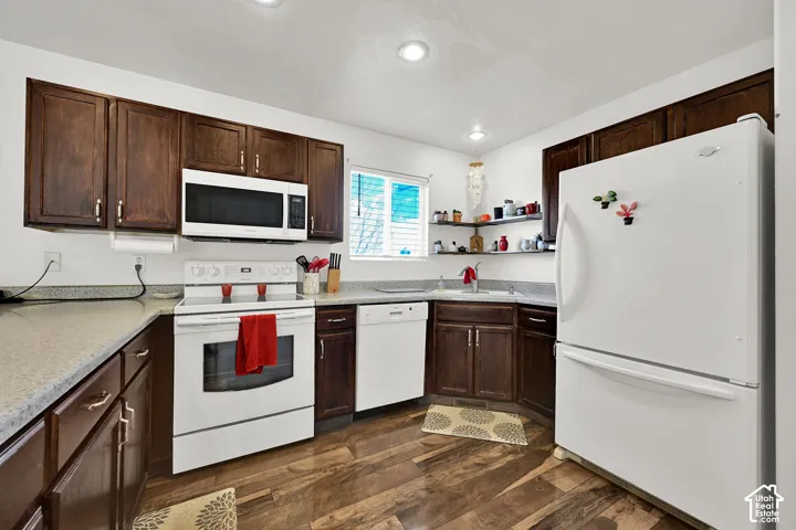 Kitchen featuring dark wood-finish cabinetry, stone-texture countertops, wood-finish flooring, recessed lighting, and corner floating shelving