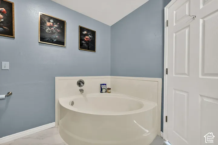 Corner soaking tub with integrated surround, chrome fixtures, and white paneled door