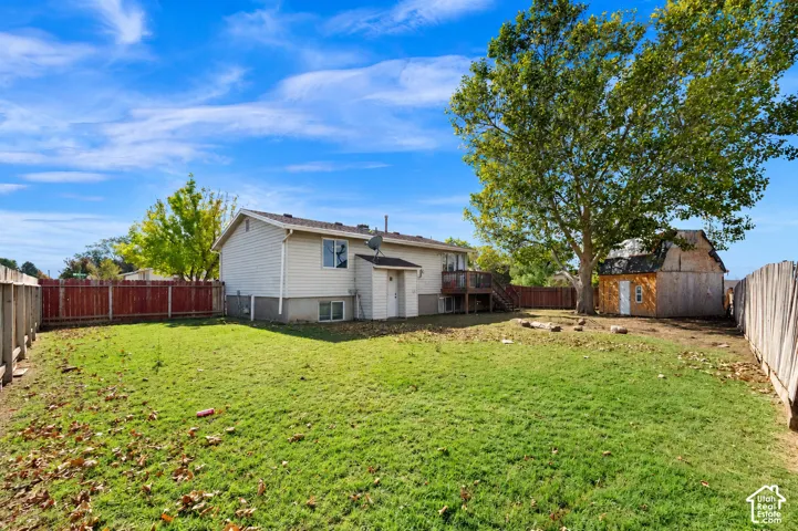 Expansive backyard featuring a fenced perimeter, mature trees, and a detached outbuilding