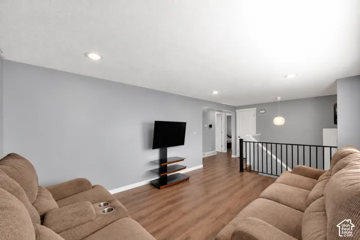 Wood-finish flooring, recessed lighting, and black metal stair railing