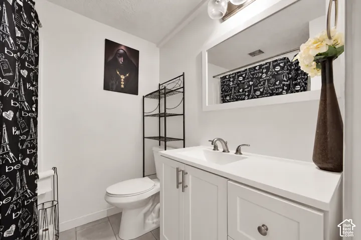 White vanity featuring a solid surface countertop, integrated sink, metal faucet, framed mirror, and tile flooring