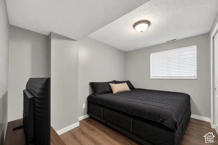 Neutral-toned room featuring wood-finish flooring, a flush-mount ceiling light, and a window with horizontal blinds