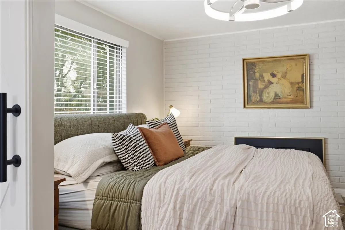 Painted brick accent wall, large window with horizontal blinds, and modern circular flush-mount ceiling lighting