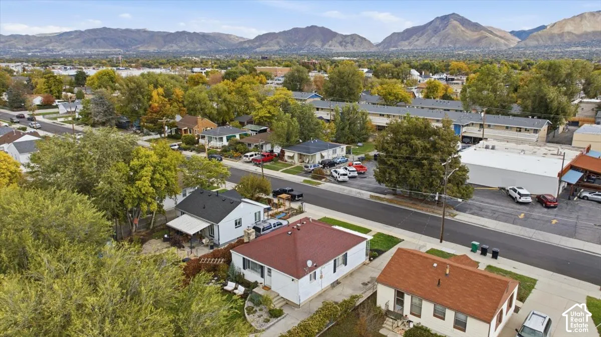 Aerial perspective of the residential property featuring mountain scenery, mature tree canopy, and established neighborhood landscaping
