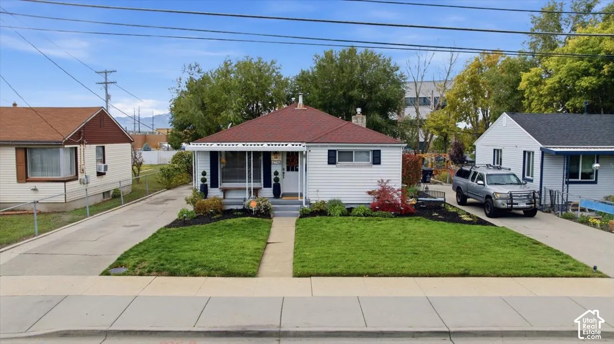 Single-story residence featuring white horizontal siding, a gabled roof with red asphalt shingles, a covered front porch, and manicured landscaping
