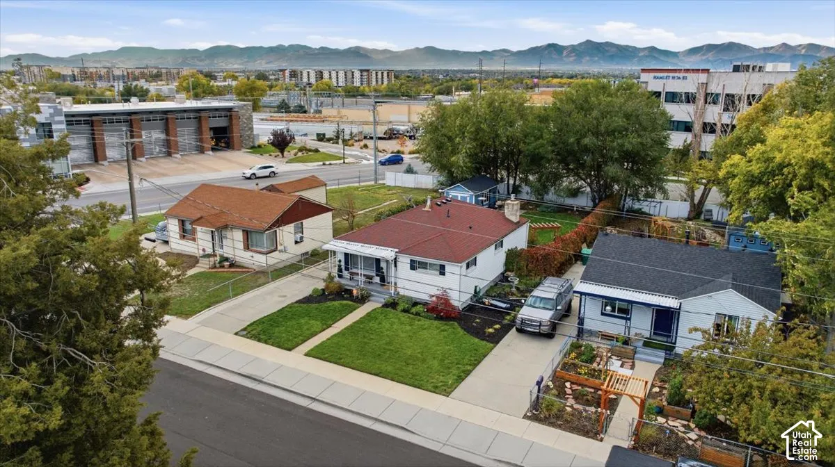 Aerial perspective of residential properties featuring concrete driveways, manicured front lawns, and mountain backdrop