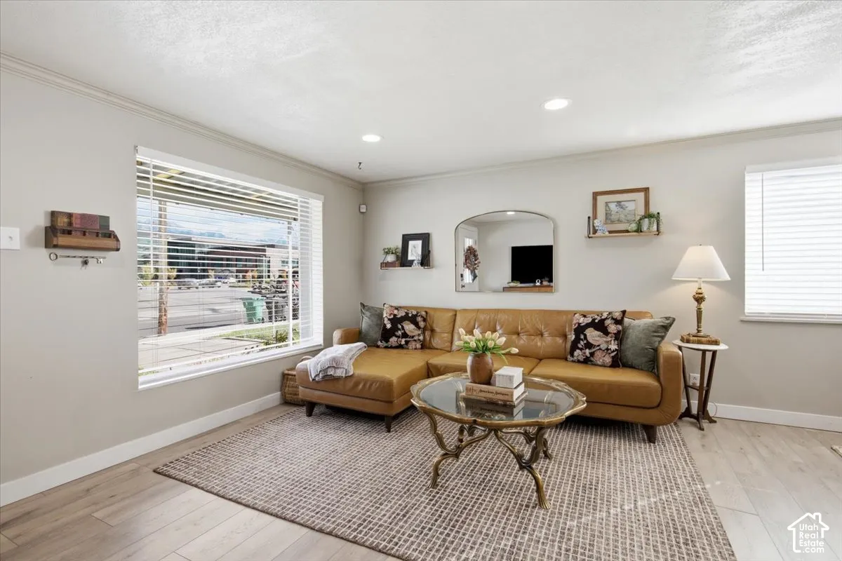 Living area featuring wood-finish flooring, recessed lighting, and large windows with horizontal blinds