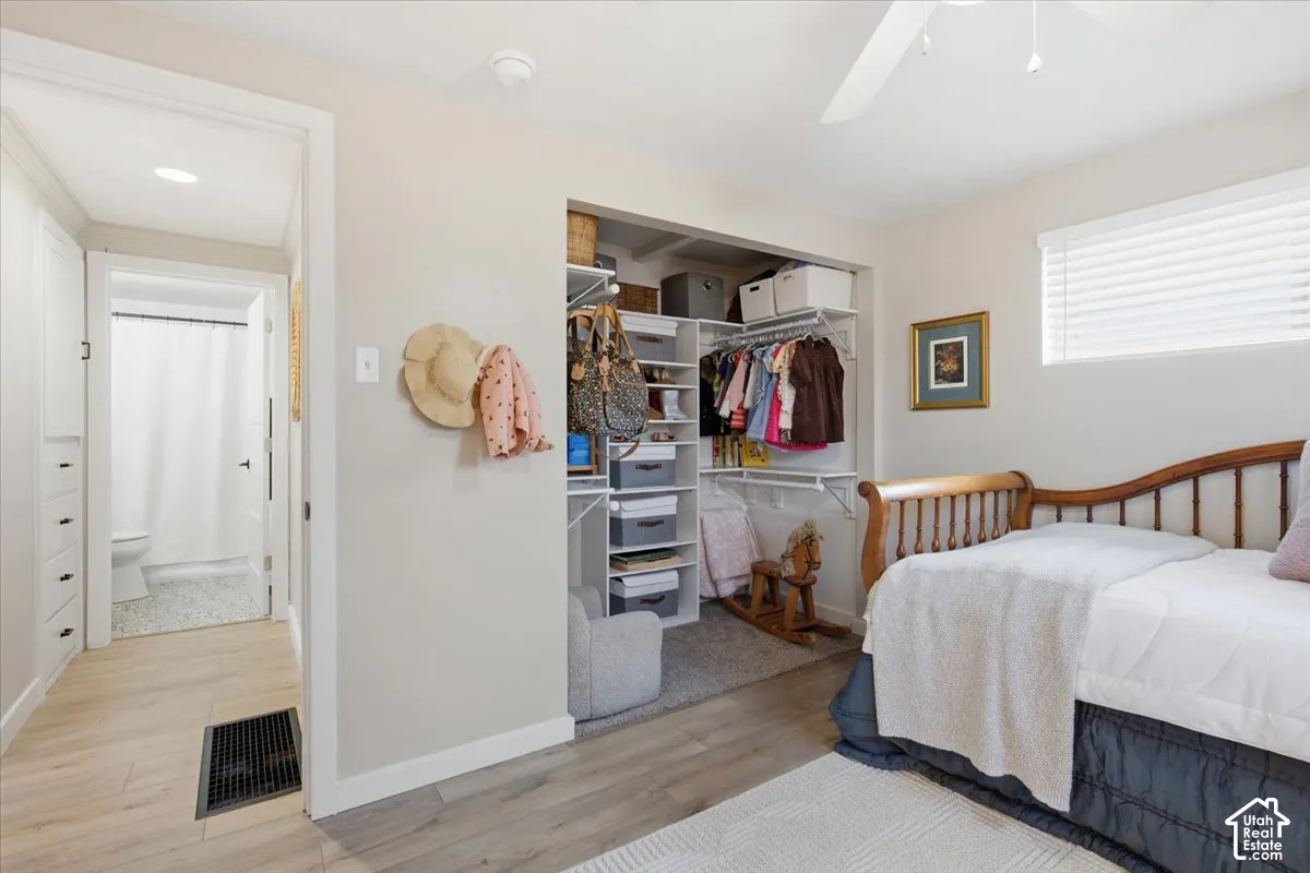 Room featuring wood-finish flooring, a built-in closet with multi-tier shelving, recessed lighting, and a ceiling fan