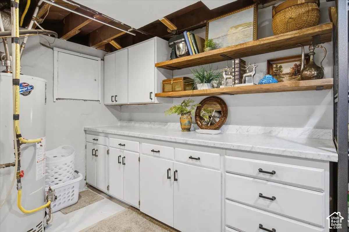 Built-in white cabinetry featuring matte black hardware, stone-finish countertops, and natural wood-finish open shelving