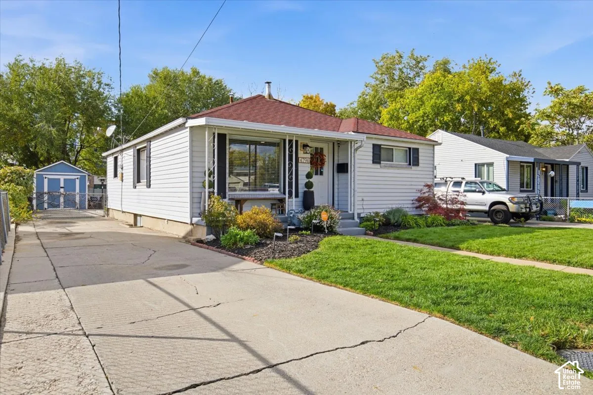 Exterior featuring horizontal siding, a hipped roof, a covered front entryway, an extended concrete driveway, and a detached storage shed