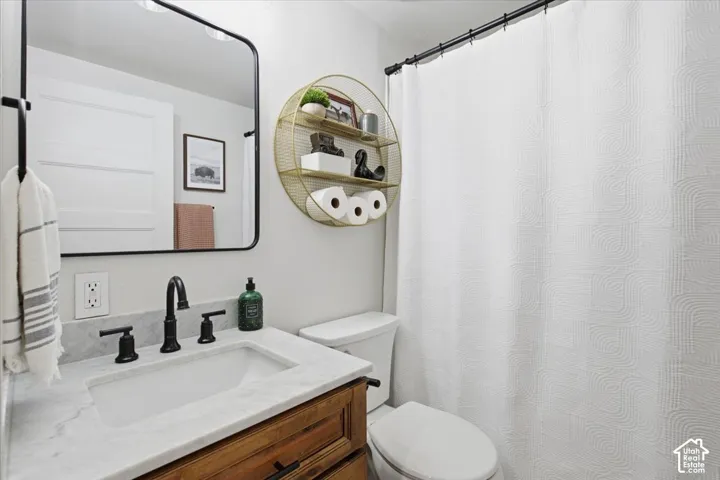 Vanity featuring a natural stone countertop with an integrated basin, matte black widespread faucet, wood-finish cabinetry, and a rectangular mirror with a matching matte black frame