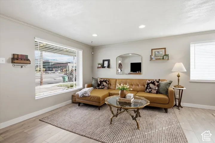 Living area featuring wood-finish flooring, recessed lighting, and large windows with horizontal blinds