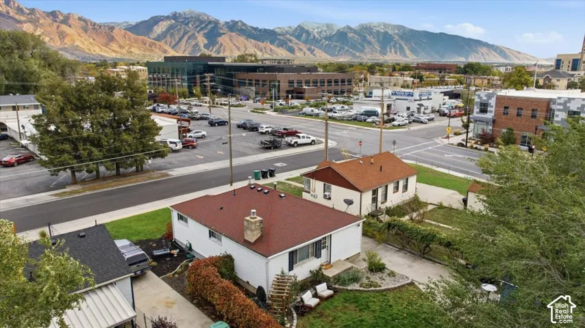 Single-story residence featuring a shingled roof, exterior masonry chimney, concrete driveway, and mountain backdrop