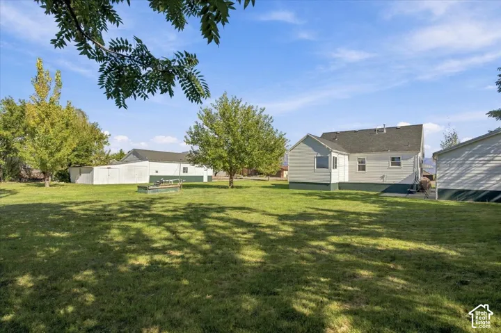 Expansive lot featuring mature trees, manicured lawn, and multiple detached outbuildings