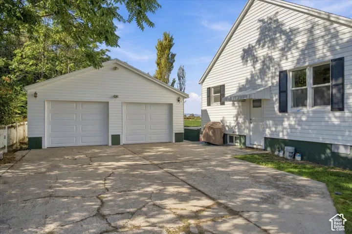 White siding exterior with black shutters and a detached two-car garage