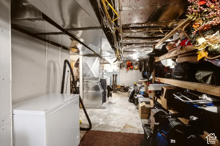 Unfinished utility area featuring exposed metallic ductwork, concrete flooring, and reflective ceiling insulation