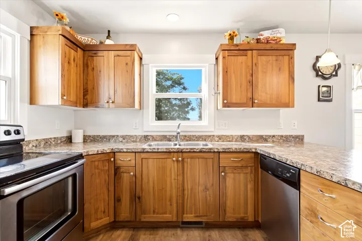 Kitchen featuring natural wood-finish cabinetry, stone-patterned laminate countertops, double-basin stainless steel sink, and stainless steel appliances