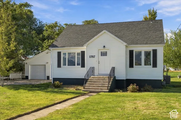 Single-story residence featuring horizontal lap siding, a gable roof, black decorative shutters, metal stair railings, and a detached garage