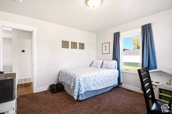 Neutral-toned room featuring plush carpeting, a wide window with exterior natural light exposure, white-painted door trim, and a flush-mount ceiling light fixture