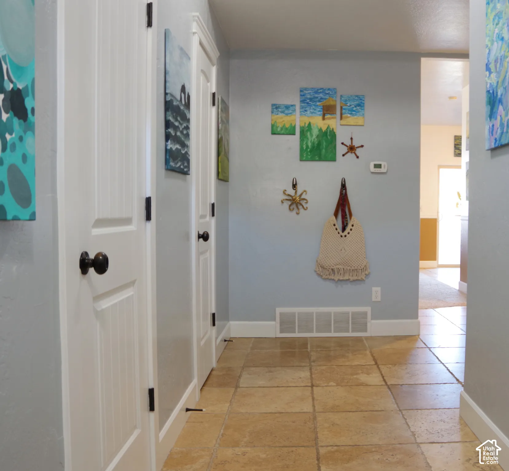 Hallway featuring tile flooring, smooth-finish walls, and multi-panel interior doors with dark hardware