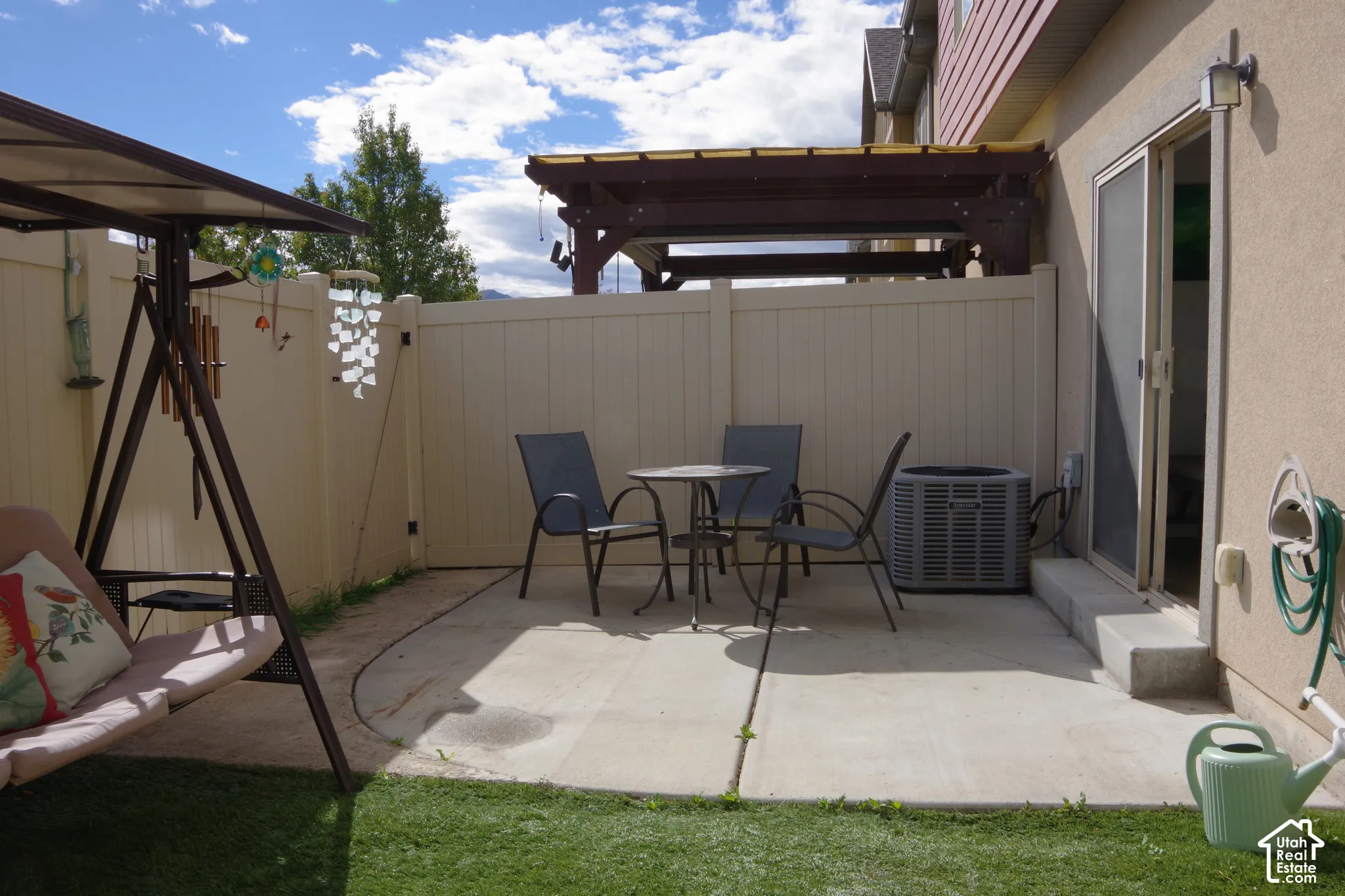 Concrete patio with a wooden pergola, enclosed by a vinyl privacy fence