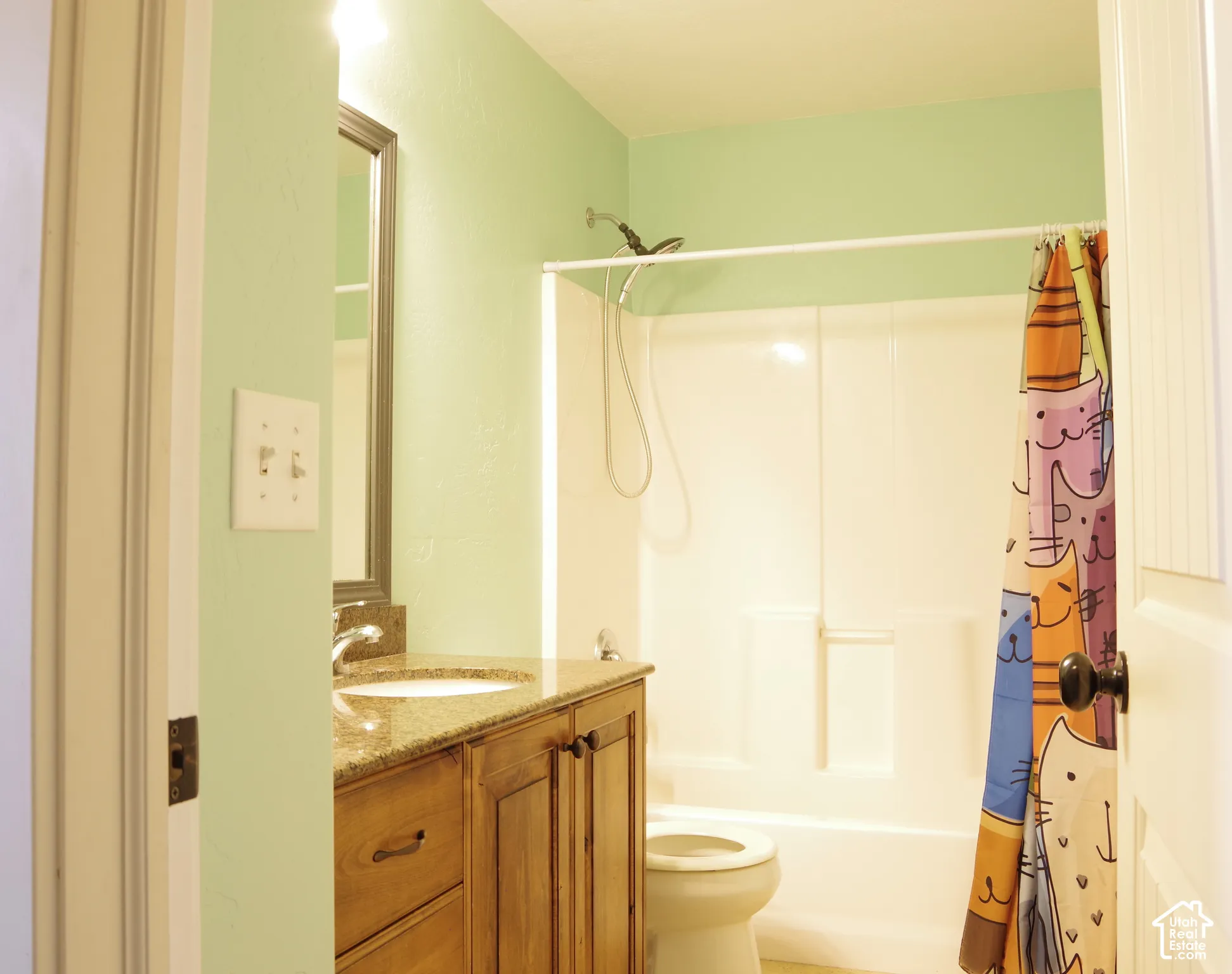 Bathroom featuring a wood-finish vanity with a stone-composite countertop, an integrated sink, a framed wall mirror, and a molded tub-shower surround