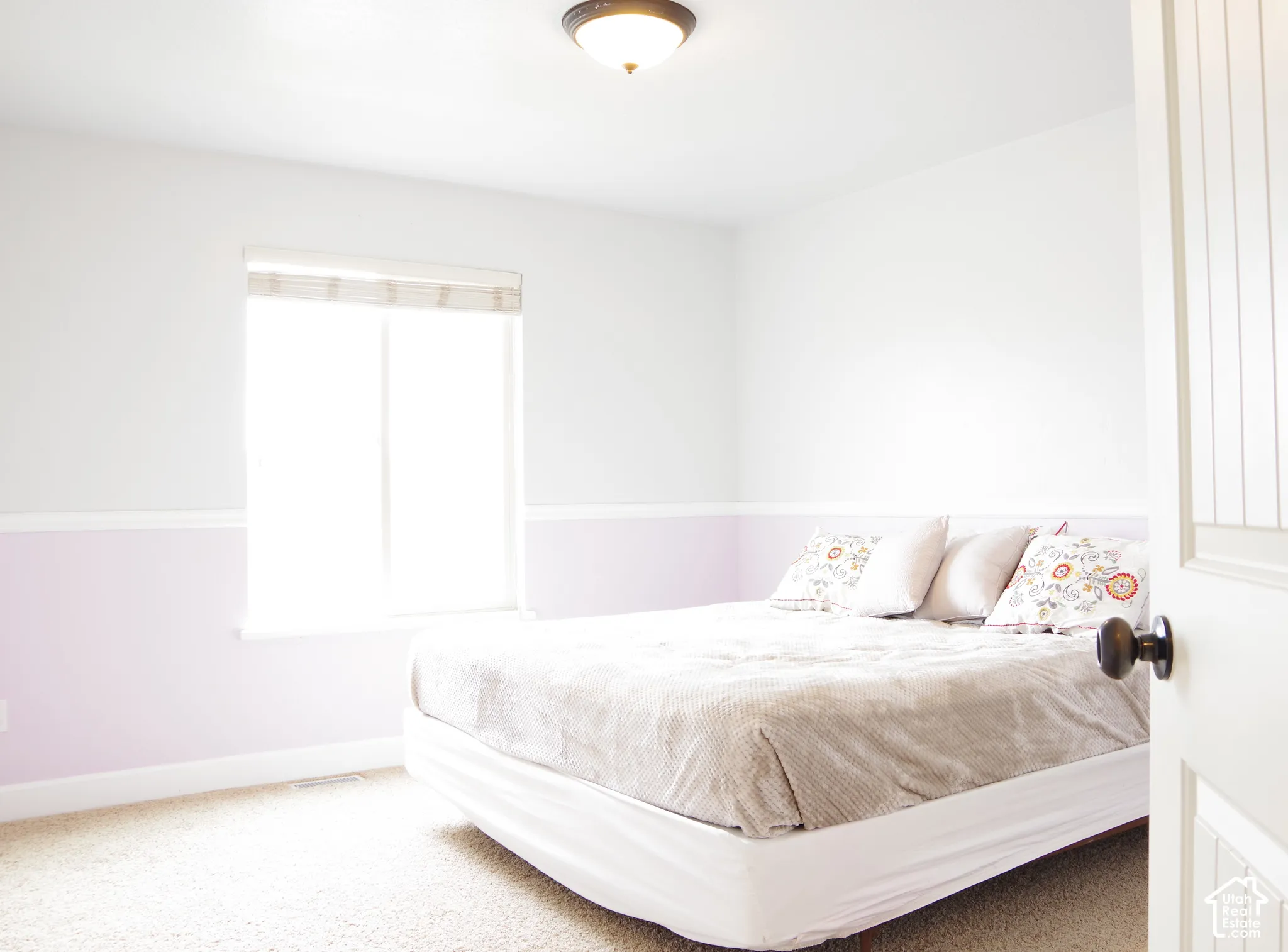 Room featuring two-tone wall paint with a chair rail, neutral wall-to-wall carpeting, a sliding window with a built-in shade, and a flush-mount ceiling light fixture