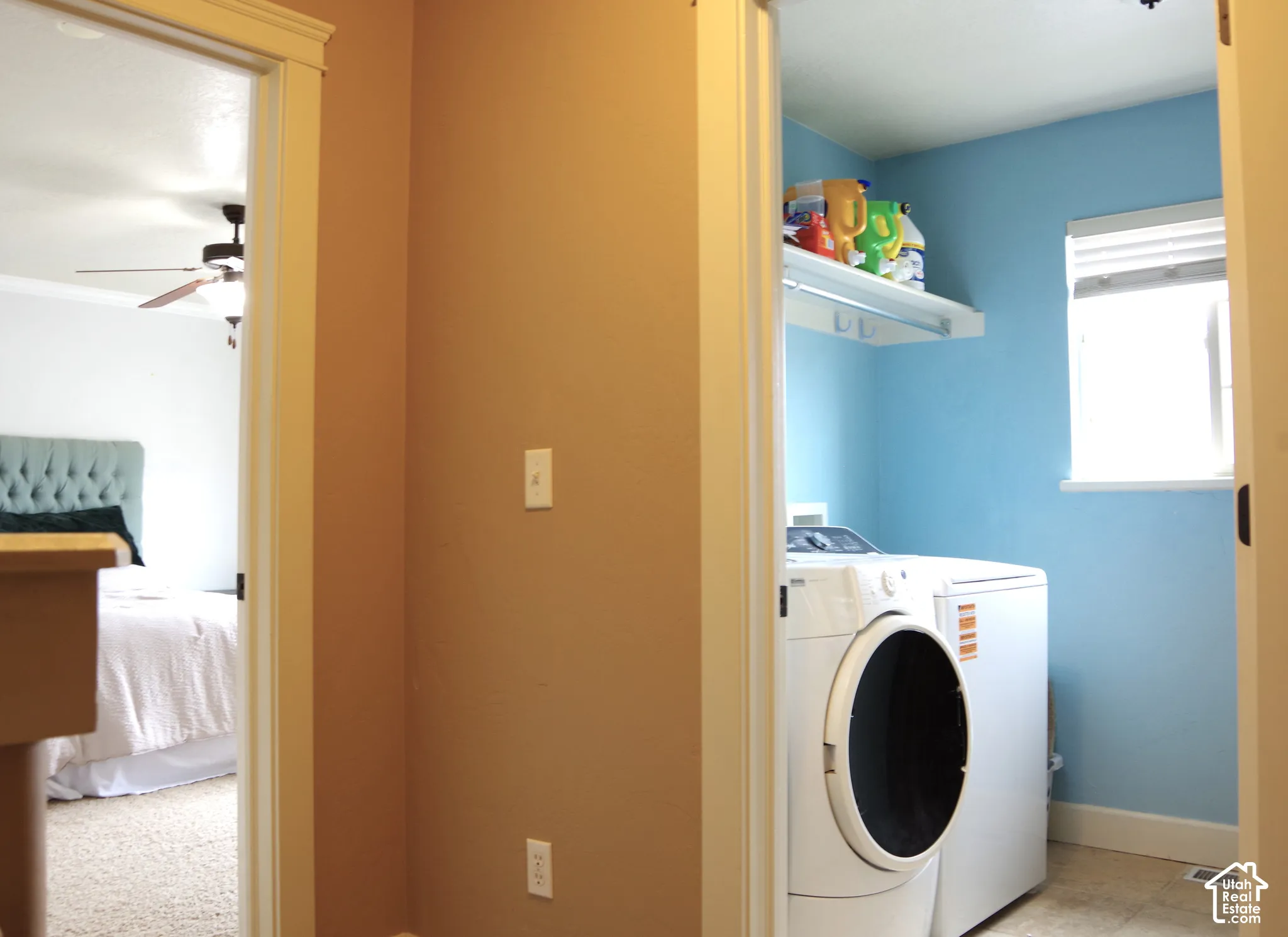Laundry area featuring a window, tile flooring, and built-in shelving with a hanging rod