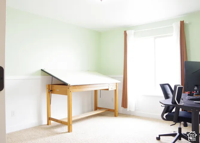 Room featuring neutral carpeting, white wainscoting, and a large window
